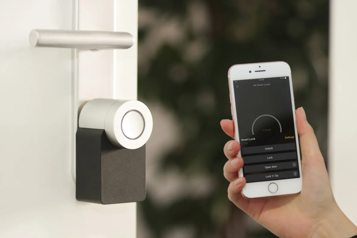 Smartphone abriendo cerradura inteligente Nuki en puerta de entrada